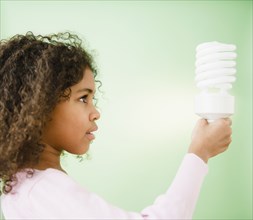 Mixed race girl holding CFL lightbulb