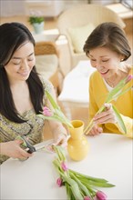 Japanese mother and daughter putting flowers into vase
