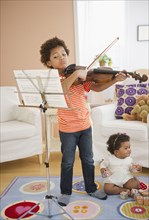 Black boy practicing violin in living room