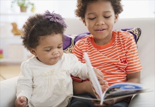 Black brother reading book to sister