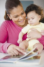 Mixed race mother reading book to baby