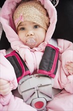 Mixed race baby in car seat sucking pacifier