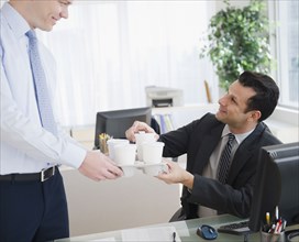 Businessman bringing coffee to co-worker