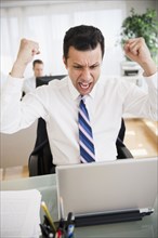 Angry mixed race businessman shouting in laptop