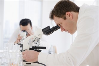 Caucasian scientist peering into microscope