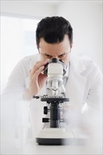 Mixed race scientist looking into microscope