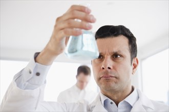 Mixed race scientist holding beaker of liquid