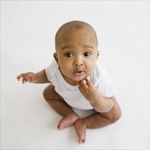 Mixed race baby girl sitting on floor