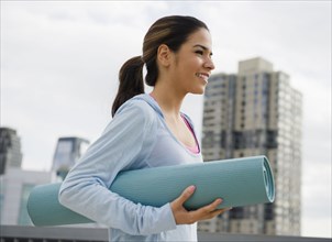 Hispanic woman carrying yoga mat