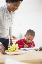 Black mother helping son with homework