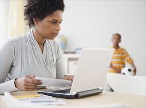 Black woman paying bills online with laptop