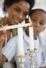 Black mother and son lighting candles together