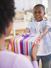 Black son handing mother a gift