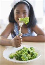 Black girl eating broccoli