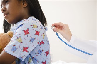 Doctor using stethoscope on Black girl in hospital
