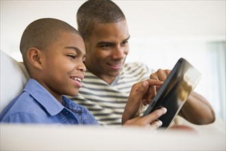 Father and son using digital tablet together