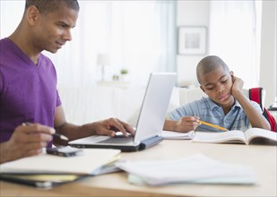 Father working and son doing homework