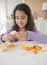 Mixed race girl peeling an orange