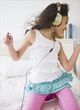 Mixed race girl listening to music on headphones