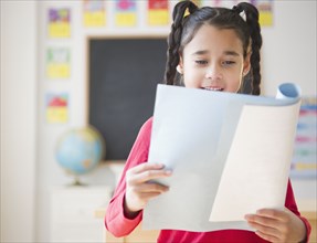 Mixed race girl reading report in school