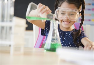 Mixed race girl pouring liquid in chemistry class