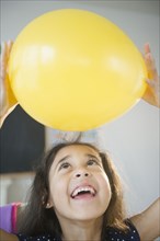 Mixed race girl holding yellow balloon