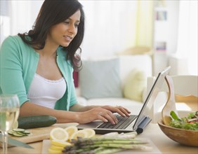 Mixed race woman using laptop in kitchen