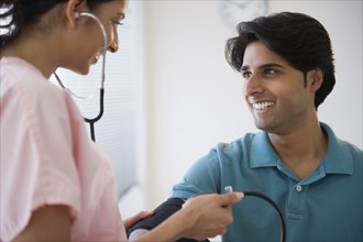 Mixed race nurse taking patient's blood pressure