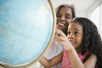 African American grandmother and granddaughter looking at globe
