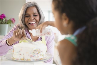 African American grandmother and granddaughter decorating a cake