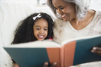 African American grandmother and granddaughter reading a book