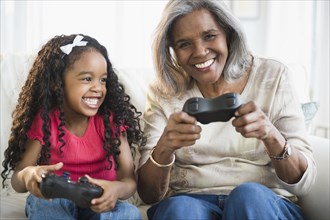 African American grandmother and granddaughter playing video games