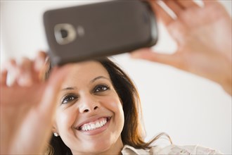Cape Verdean woman taking photograph with cell phone