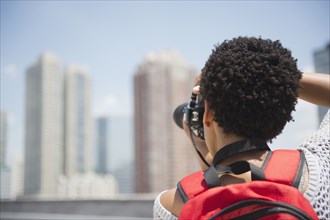 African American woman taking photographs of cityscape