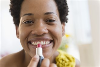 African American woman putting on lipstick