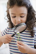 Mixed race girl looking at flower with magnifying glass
