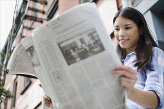 Asian woman reading newspaper