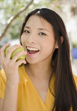 Asian woman eating green apple