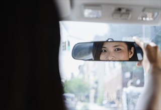 Asian woman adjusting rear-view mirror