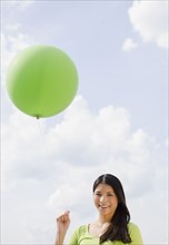 Asian woman holding green balloon