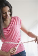 Hispanic teenager measuring her waist