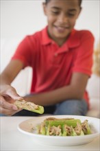 Hispanic boy eating peanut butter on celery