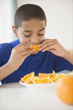 Hispanic boy eating orange sections