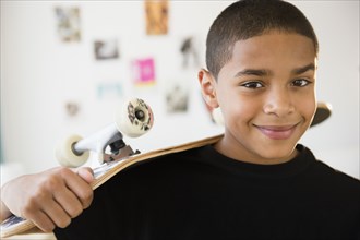 Hispanic boy holding skateboard