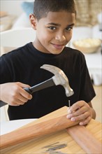 Hispanic boy using hammer and nails