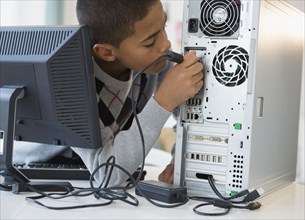 Hispanic boy plugging in computer