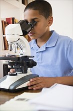Hispanic boy using microscope