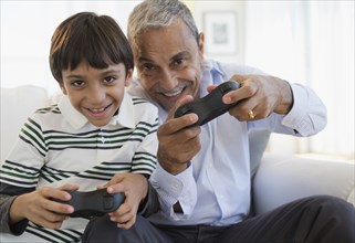 Hispanic grandfather and grandson playing video game