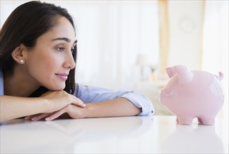 Caucasian businesswoman examining piggy bank