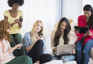 Women using technology on sofa